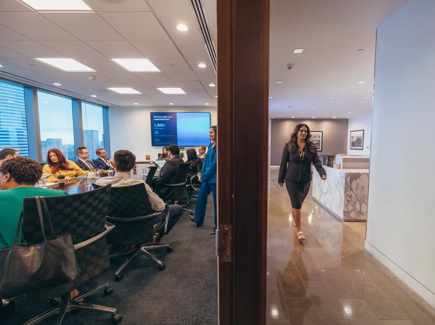People meeting in office conference room with woman walking by
