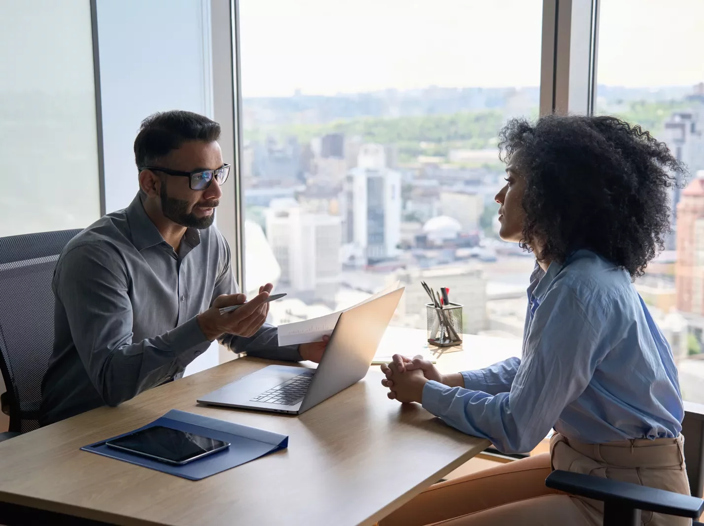 Man and woman interviewing across a desk with a laptop