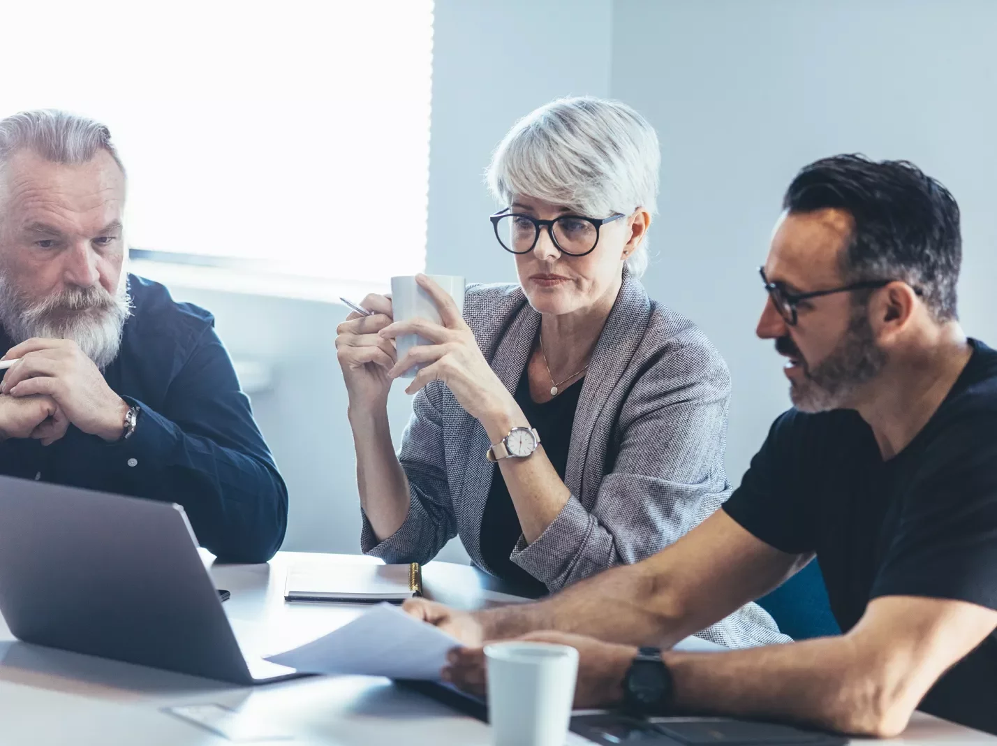 Three people meeting at a table with a laptop in conversation