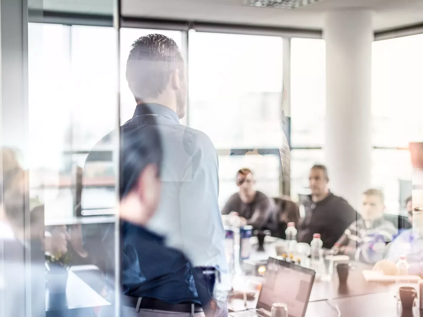 Workplace training conference room with man leading group at glass wall