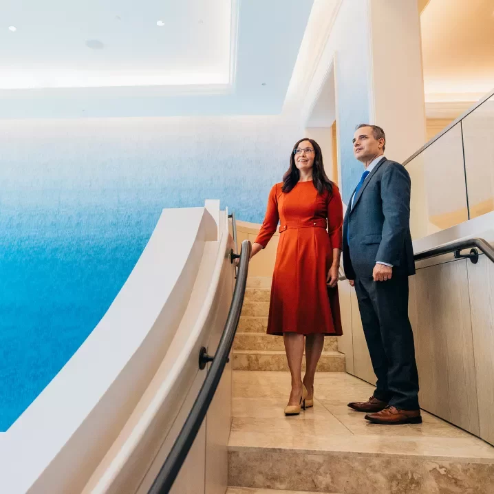 A woman in a red dress and a man in a suit standing on a staircase