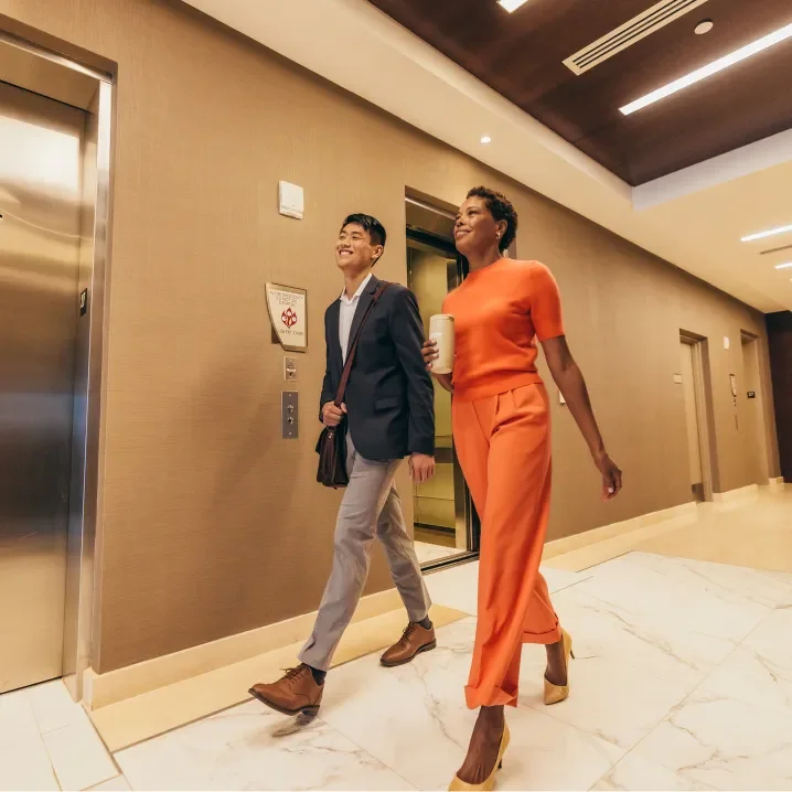 Woman and man walking near an elevator in an office building