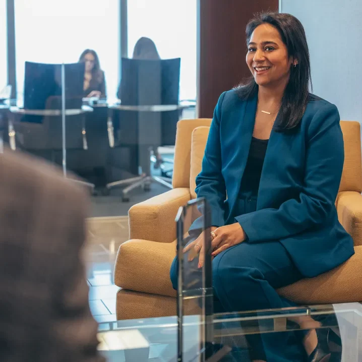 Woman in a blue suit sitting outside a conference room in an office building