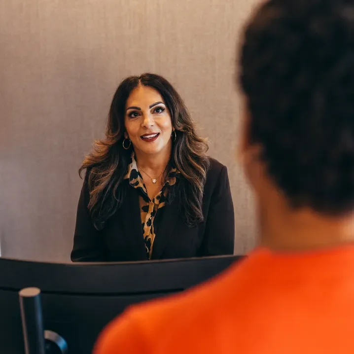 Two women in suits talking at an office desk