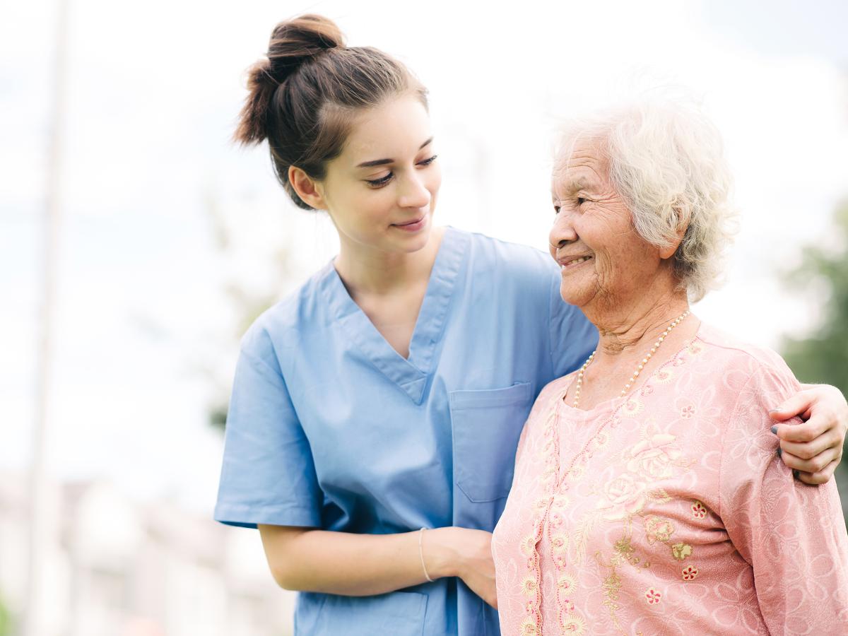 An older woman is supported by her caregiver