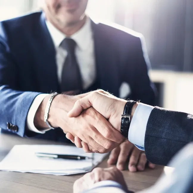 Businessmen shaking hands over a contract document