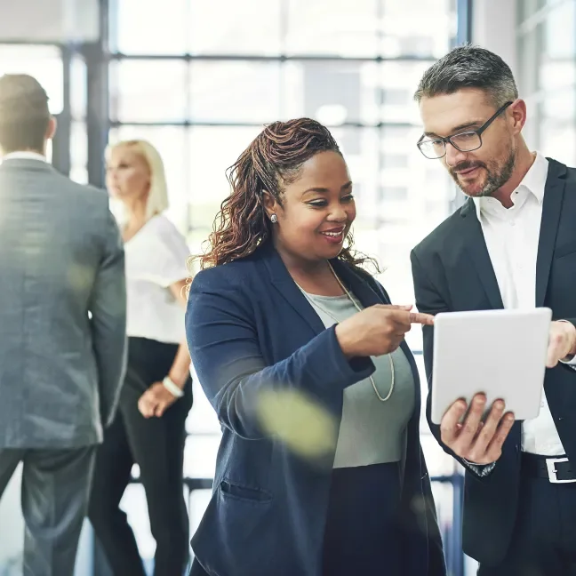 woman and man wearing suits and pointing at a document