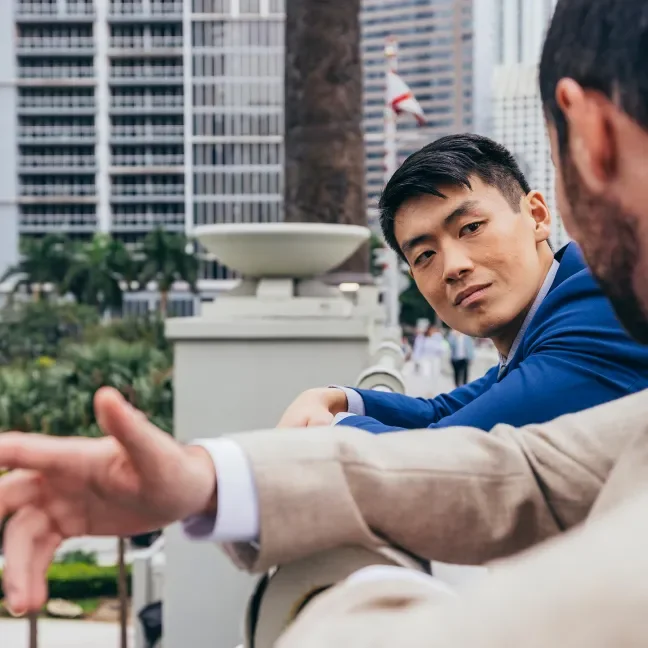 Two men in suits talking outside an office building in a city
