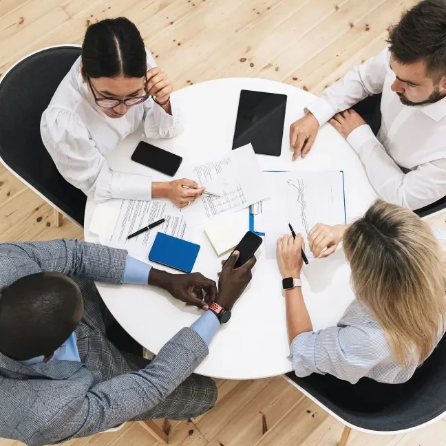 A view from above of four professionals sitting around a round table working