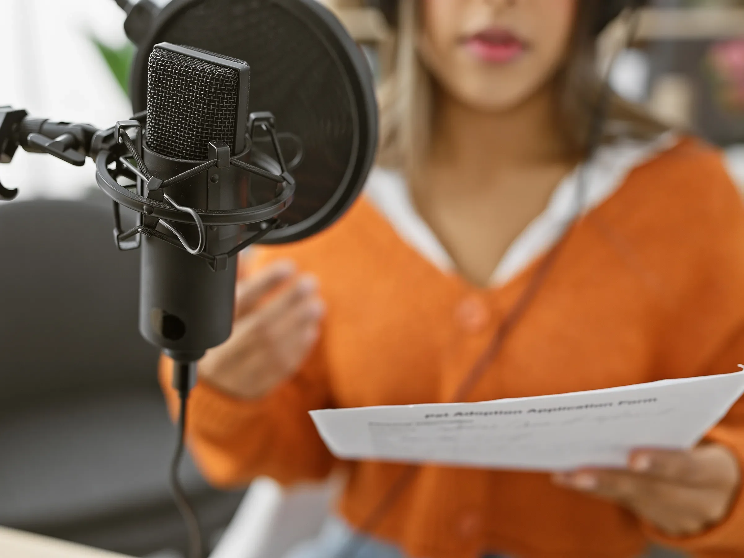 Woman in an orange shirt speaking into a microphone